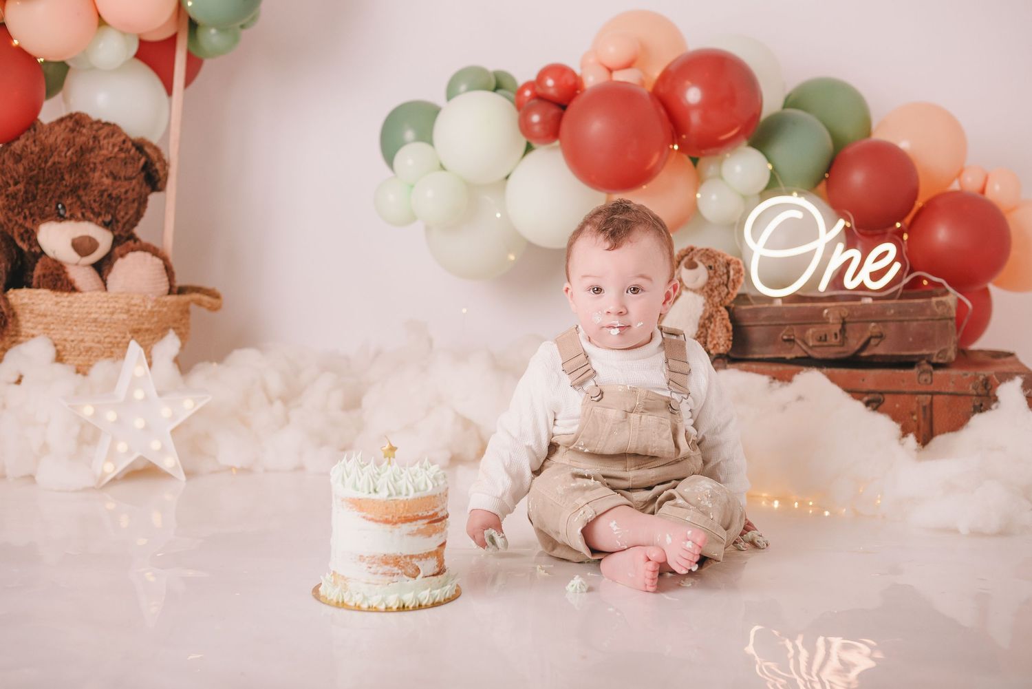 Birthday party setting with cake, balloons, and rustic decorative elements.