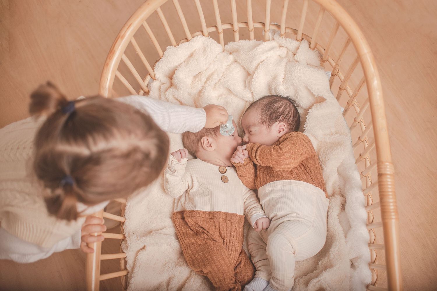 Newborn photography session with baby lying on cream colored fabric.