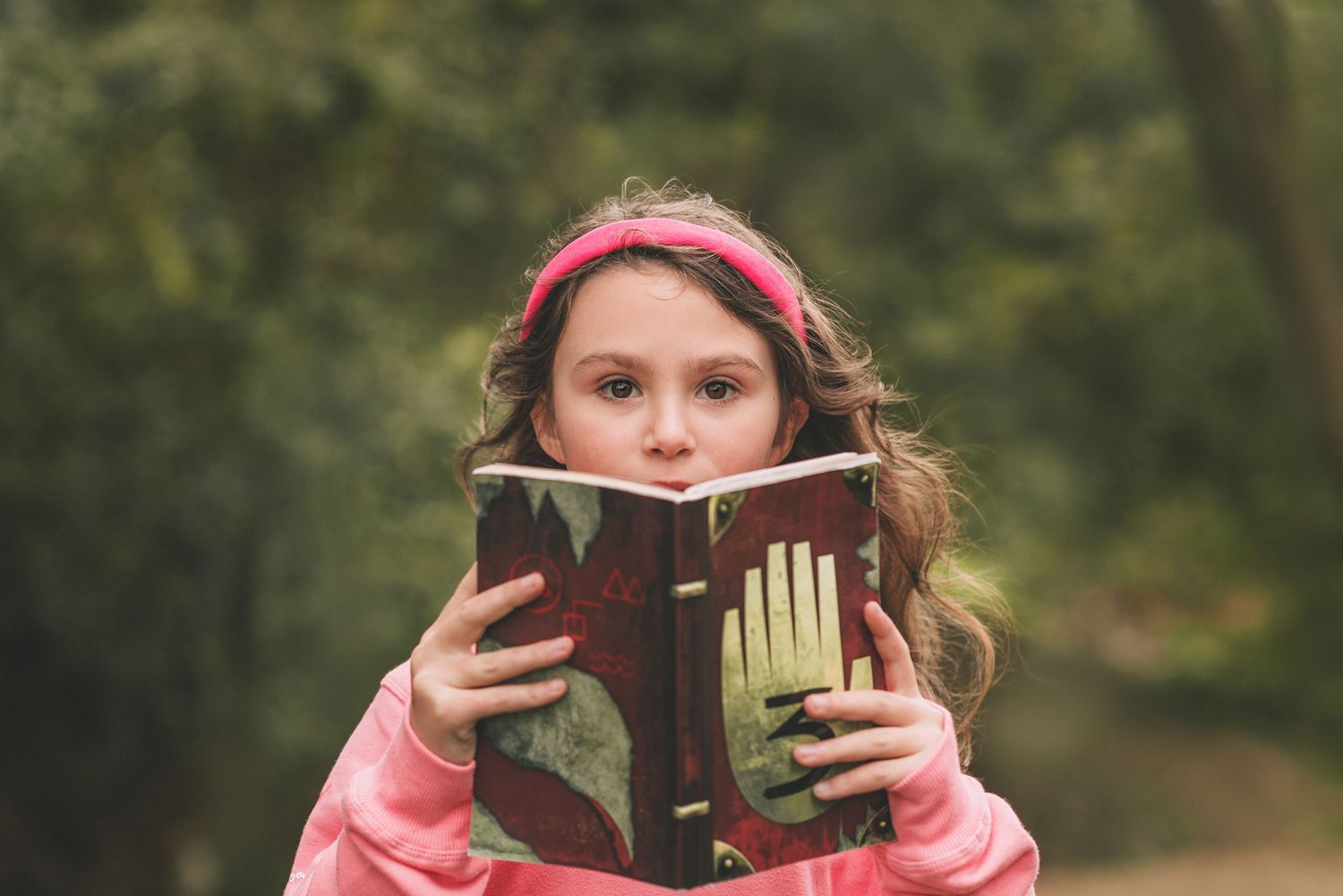 A person in a pink jacket sits outdoors while reading a book in a series of sequential photos.