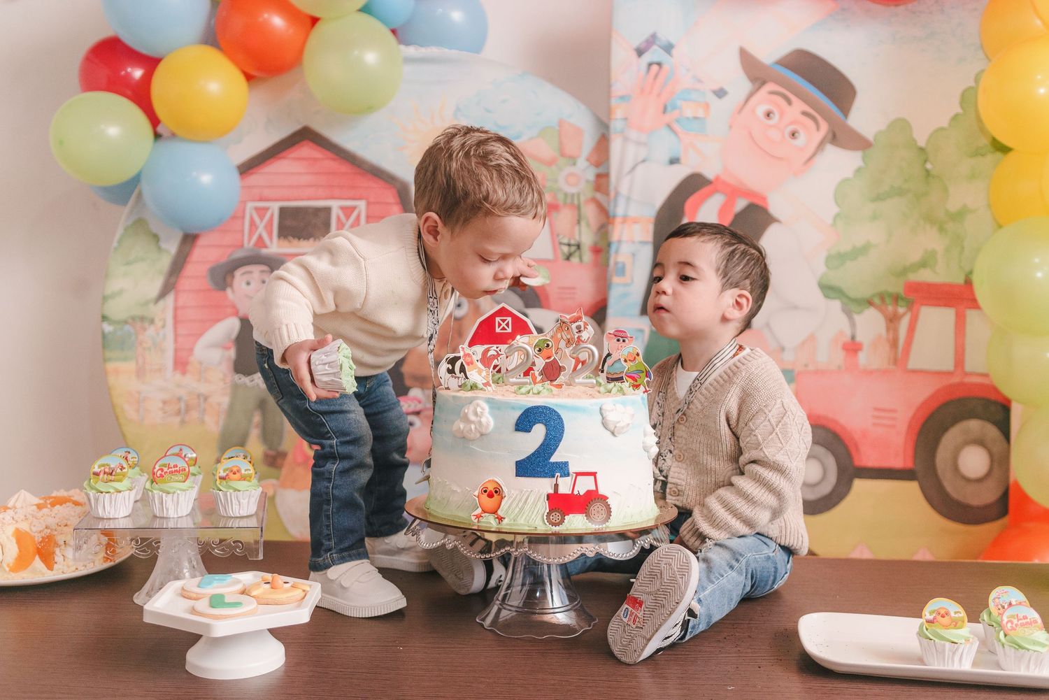 A colorful birthday party setup with balloons, cupcakes, and farm-themed decorations for a child's second birthday celebration.