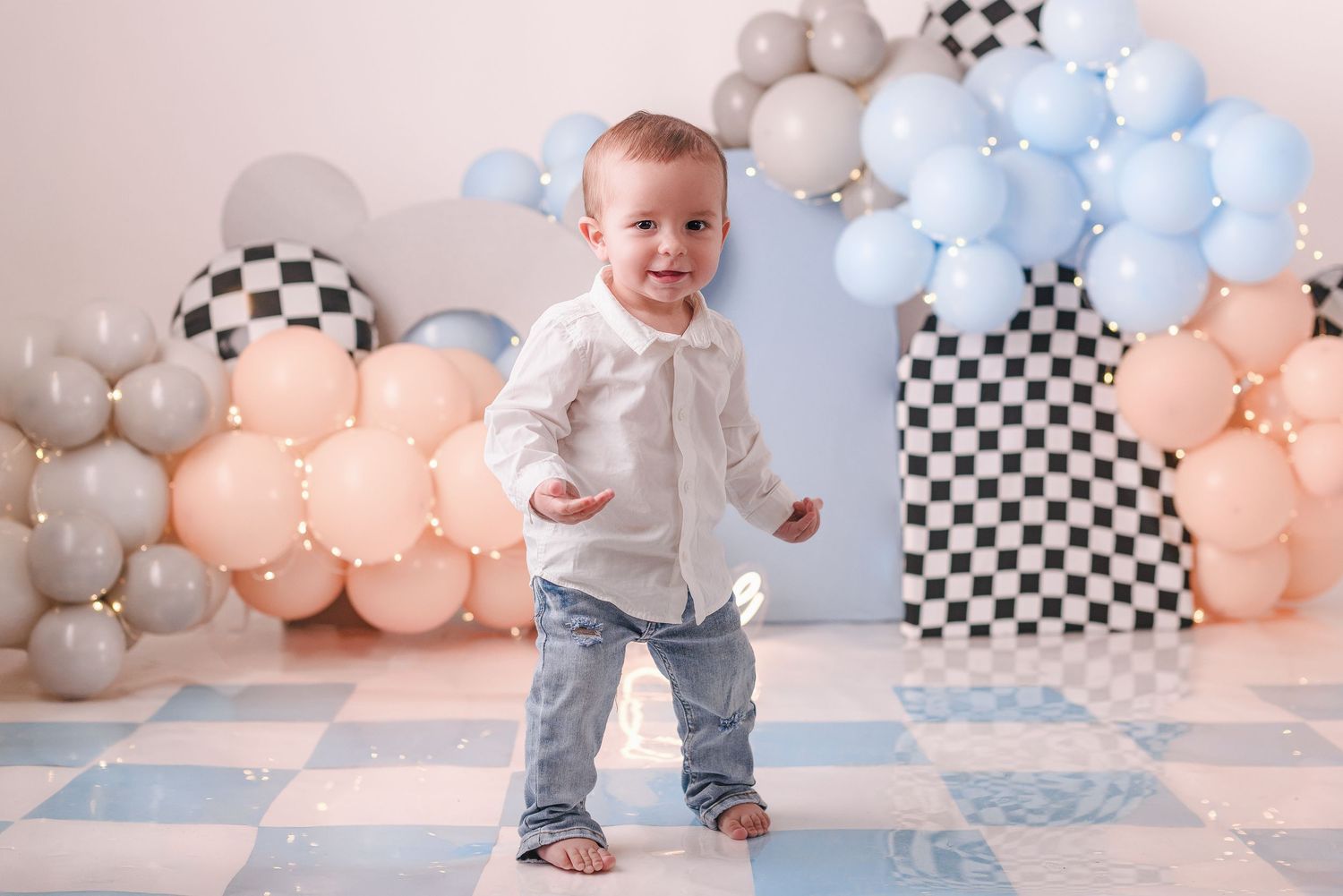 Modern first birthday setup with checkered pattern and pastel balloon decorations.