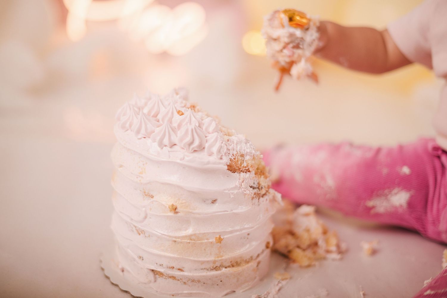 White meringue cookies with gold flakes arranged in an elegant display with pink and floral accents.
