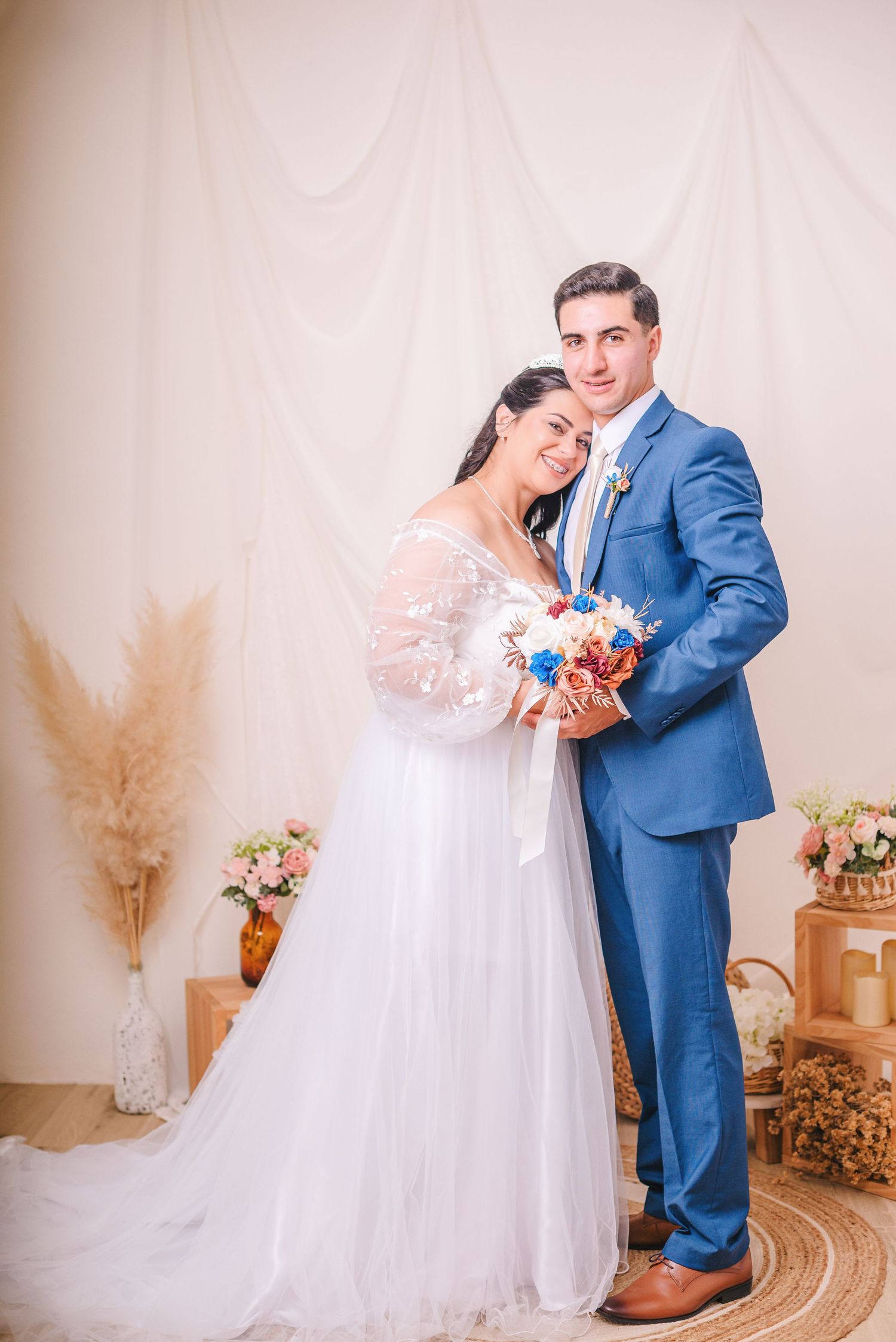 Wedding photography featuring couple in blue suit and white gown with rustic decor.