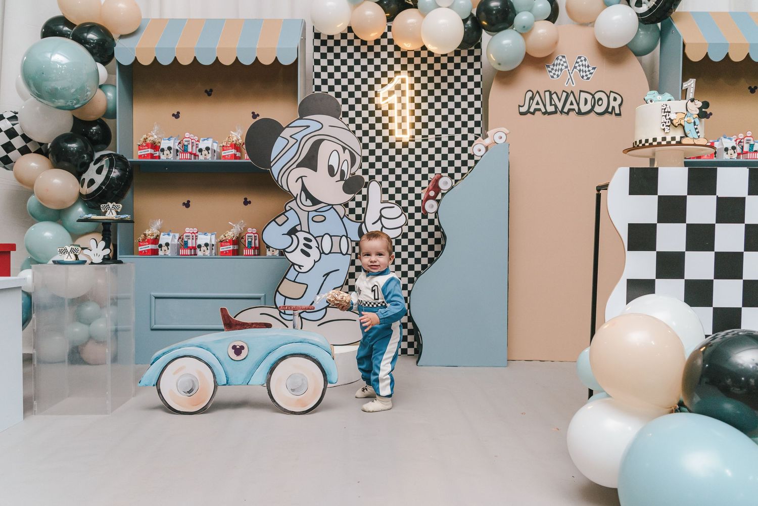 Modern racing-themed birthday party backdrop with checkered patterns and blue accents.