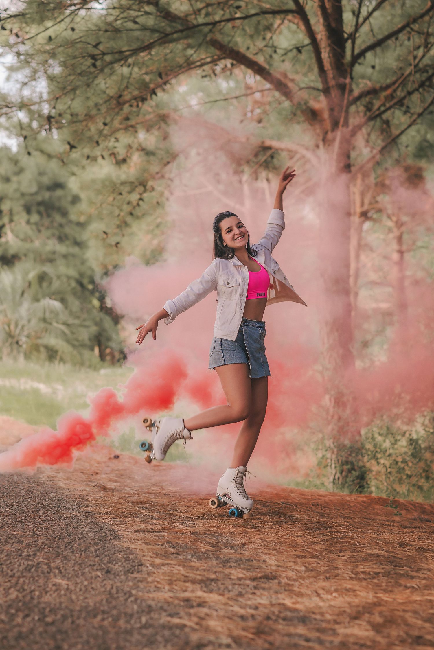 A dancer performs graceful movements on a hillside with red smoke creating a dramatic artistic effect in nature.