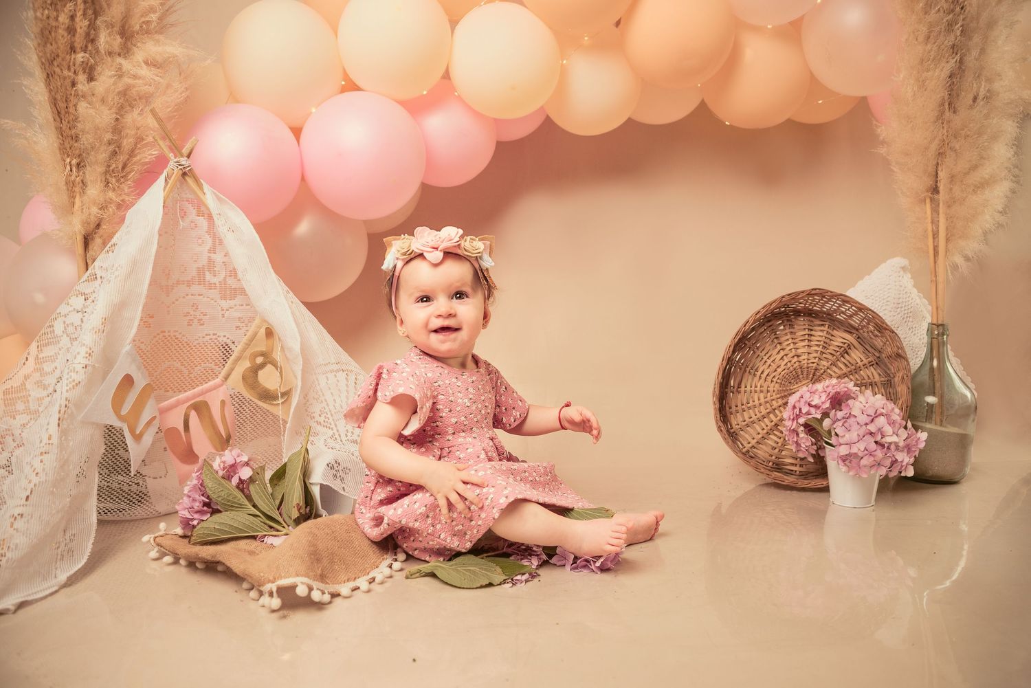 Pink balloon arch and floral decorations create a dreamy photography setup.