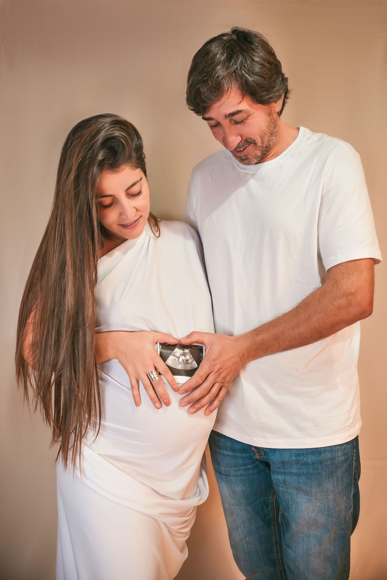 A series of five pregnancy progression photos showing a couple in white shirts documenting their growing baby bump.