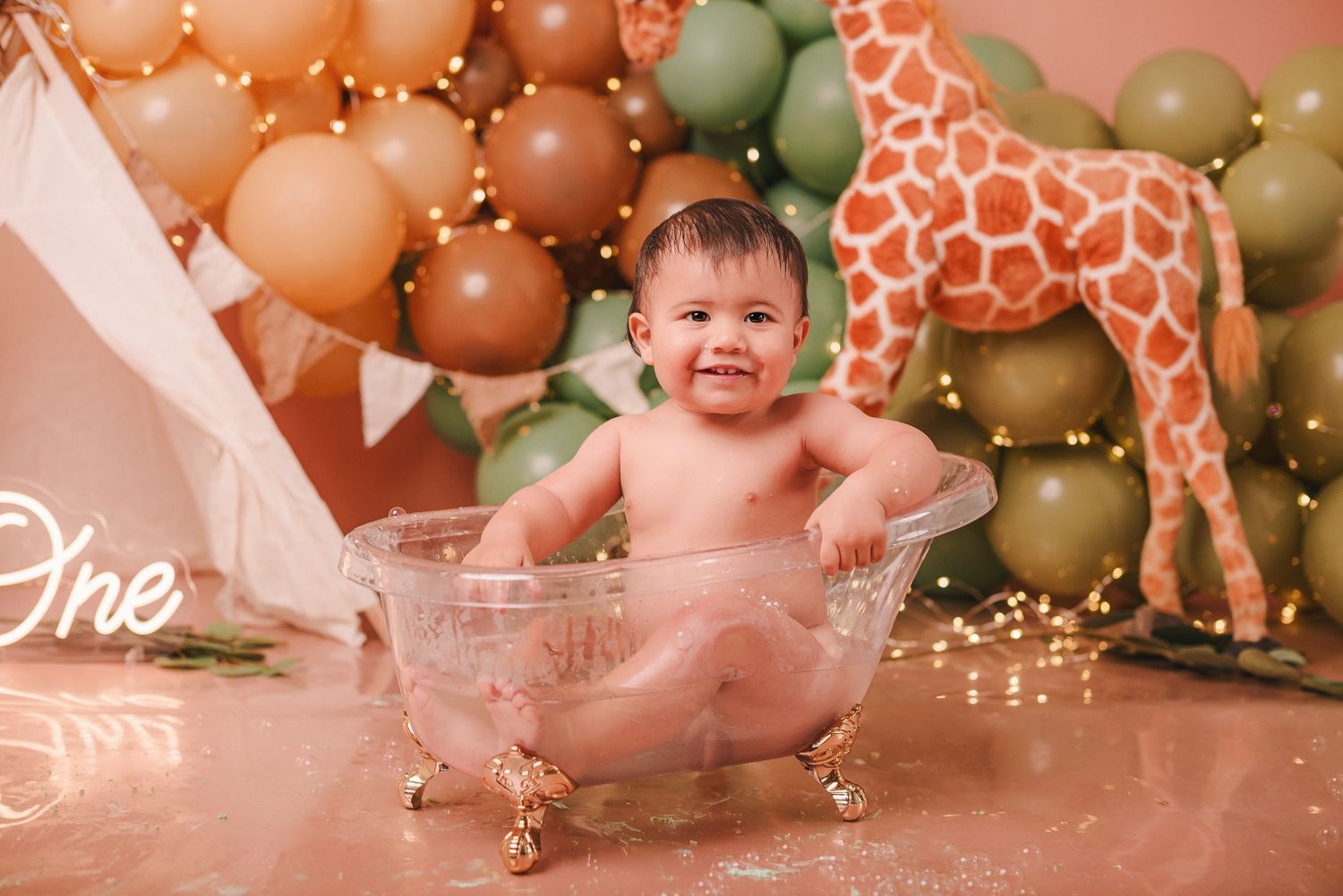 First birthday party setup with pink and gold balloons, giraffe decorations, and festive decor for cake smash photos.