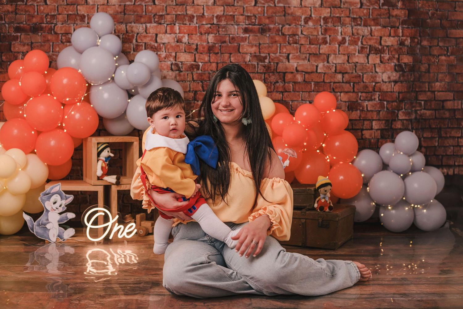 Orange and white balloon decorations against a rustic brick wall create a festive party atmosphere.