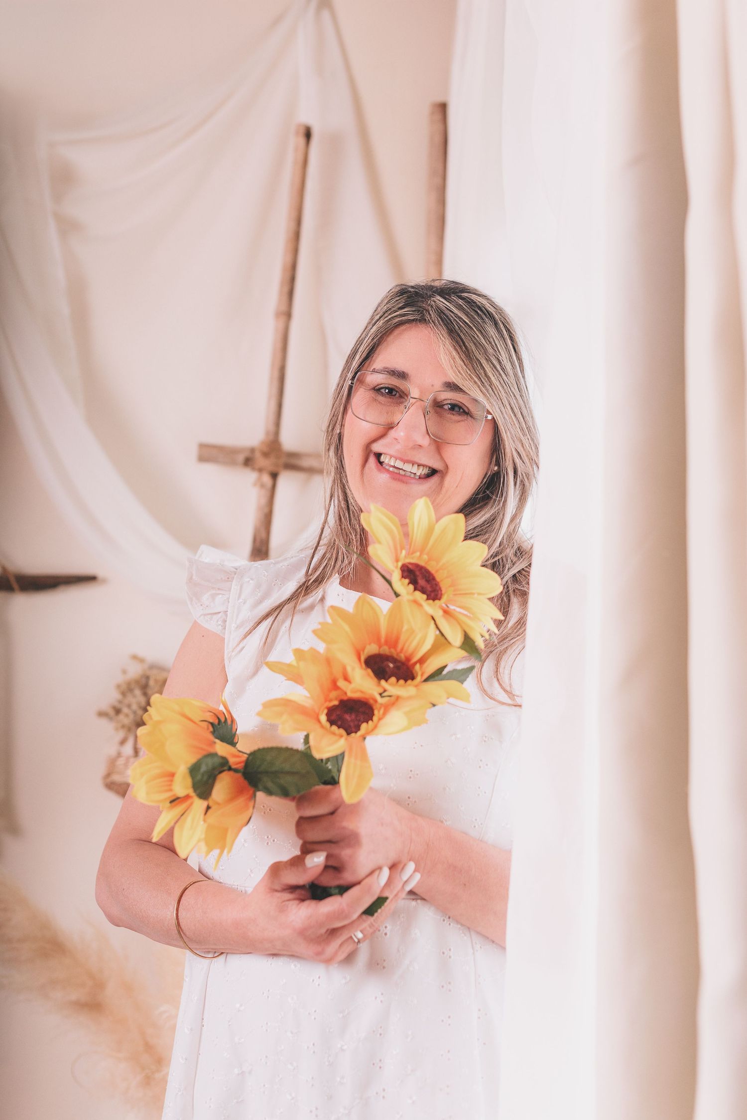A series of soft, dreamy photos featuring sunflowers being held against a white curtain backdrop in natural light.