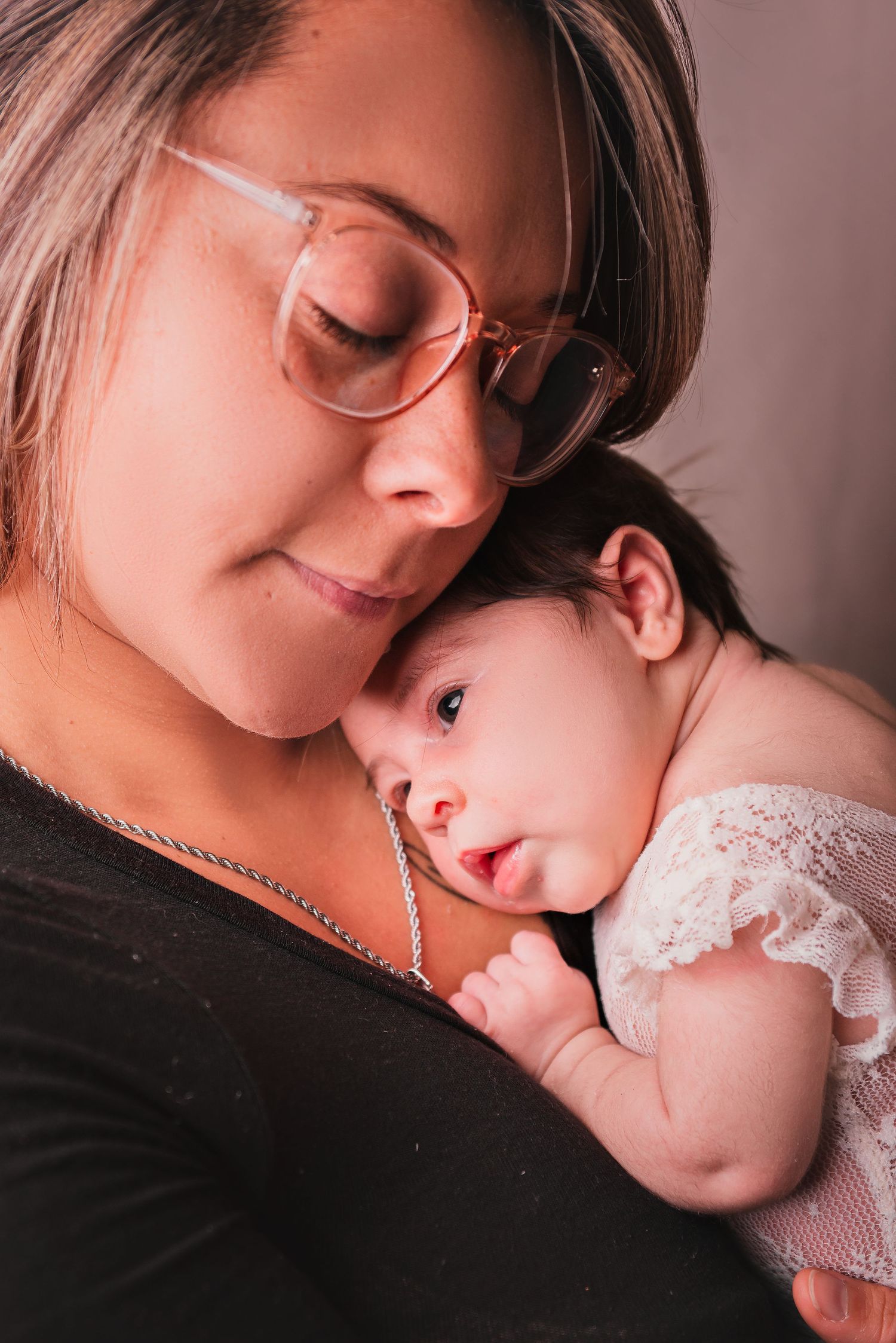 A tender moment captured in a series of photos showing a parent and baby in close embrace against a muted background.