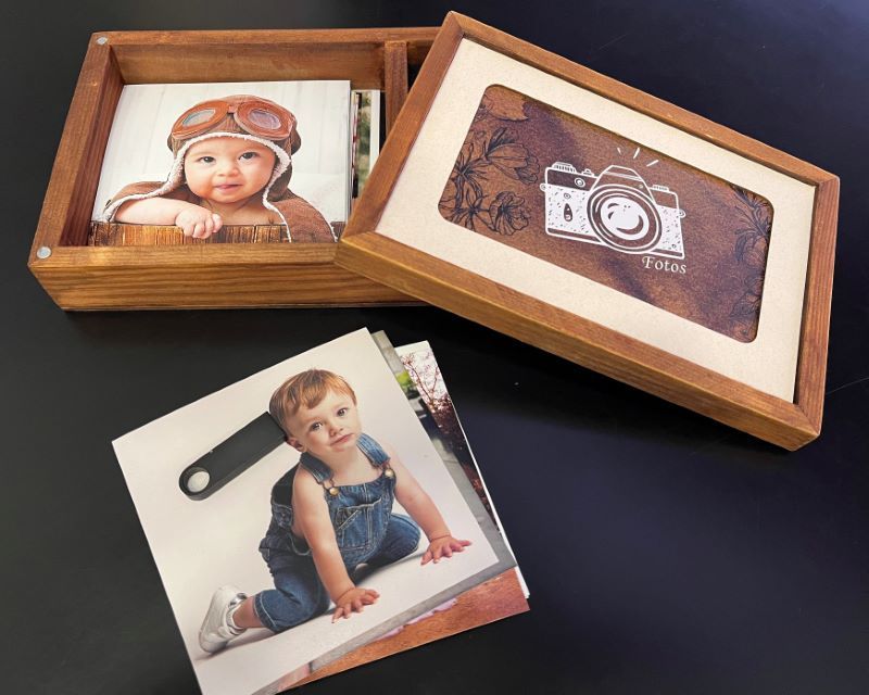 Wooden keepsake boxes displaying photographs and a decorative camera design on a dark background.