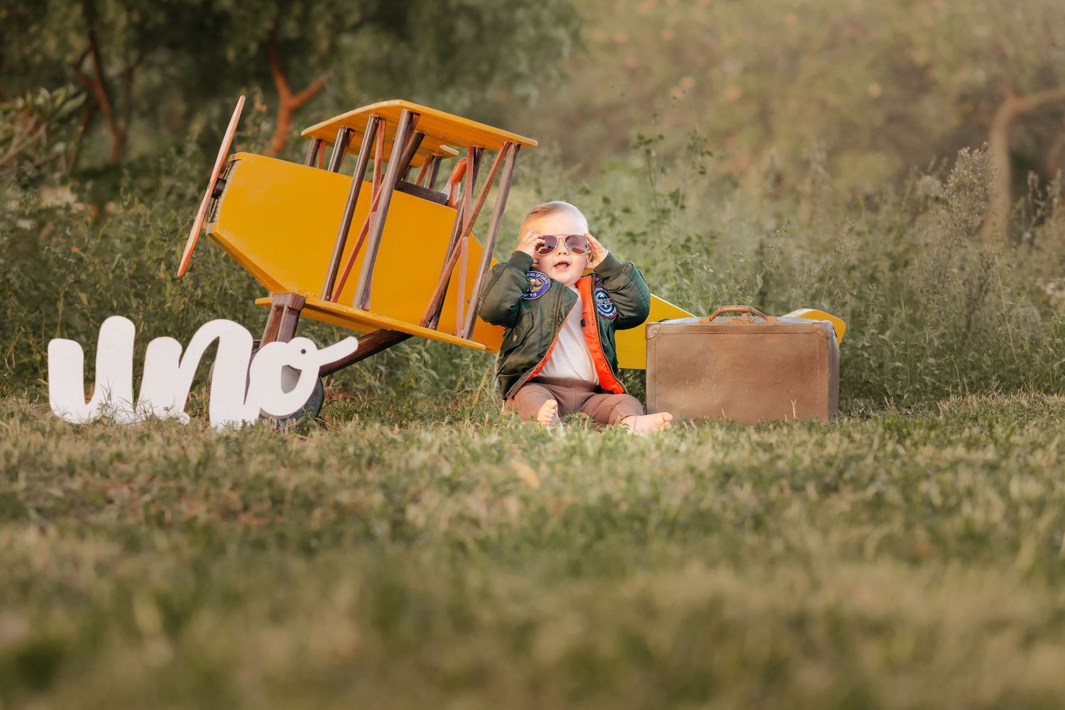 A small orange tent sits in a grassy meadow during a sunny afternoon camping trip.