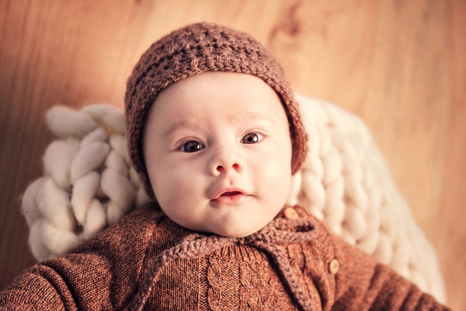 A collection of soft-toned baby photos in sepia and brown hues showing knit accessories and gentle lighting.