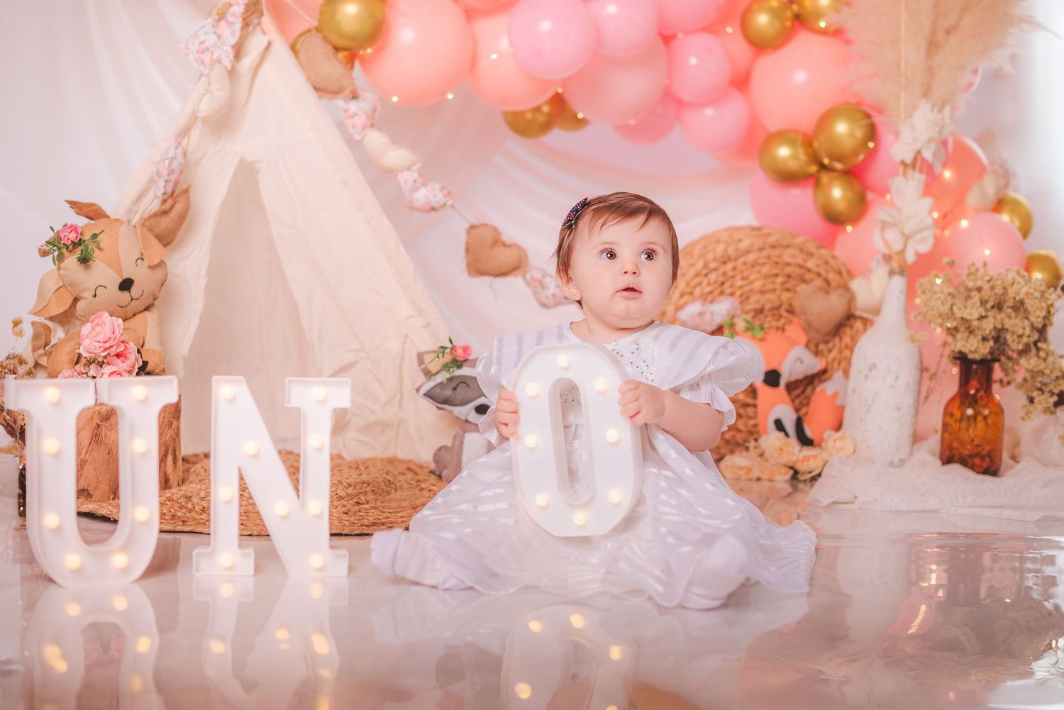 Elegant pink and gold party decorations with balloons, floral arrangements, and twinkling lights create a dreamy atmosphere.
