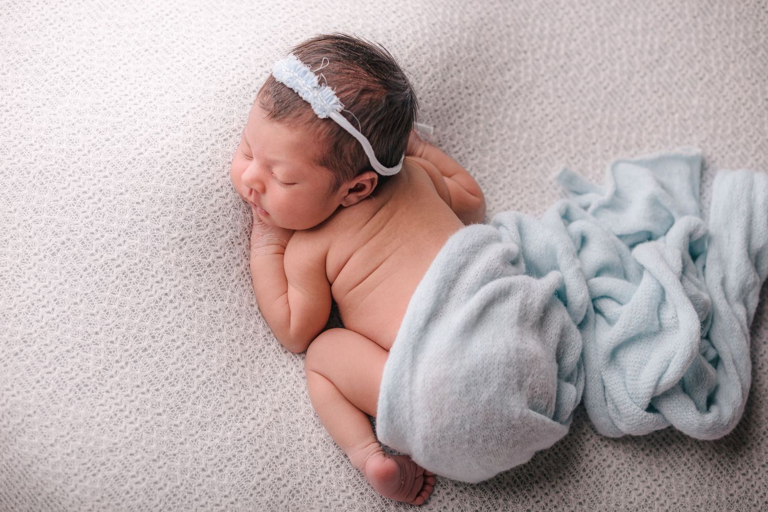 A series of soft, dreamy newborn baby photos showing peaceful sleeping poses in muted blue and grey tones.
