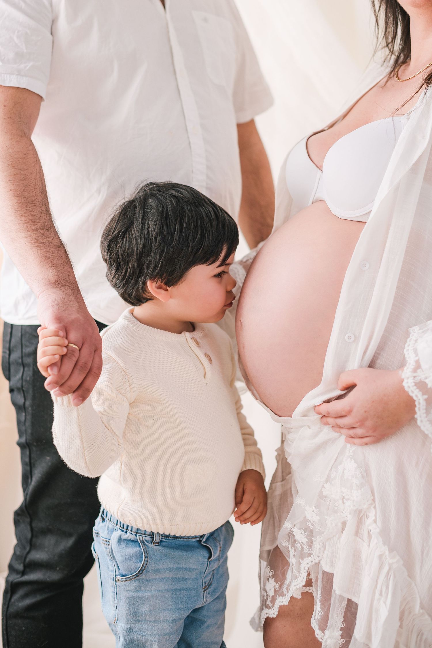 A series of maternity photos showing a pregnant belly in white clothing and jeans against a light background.