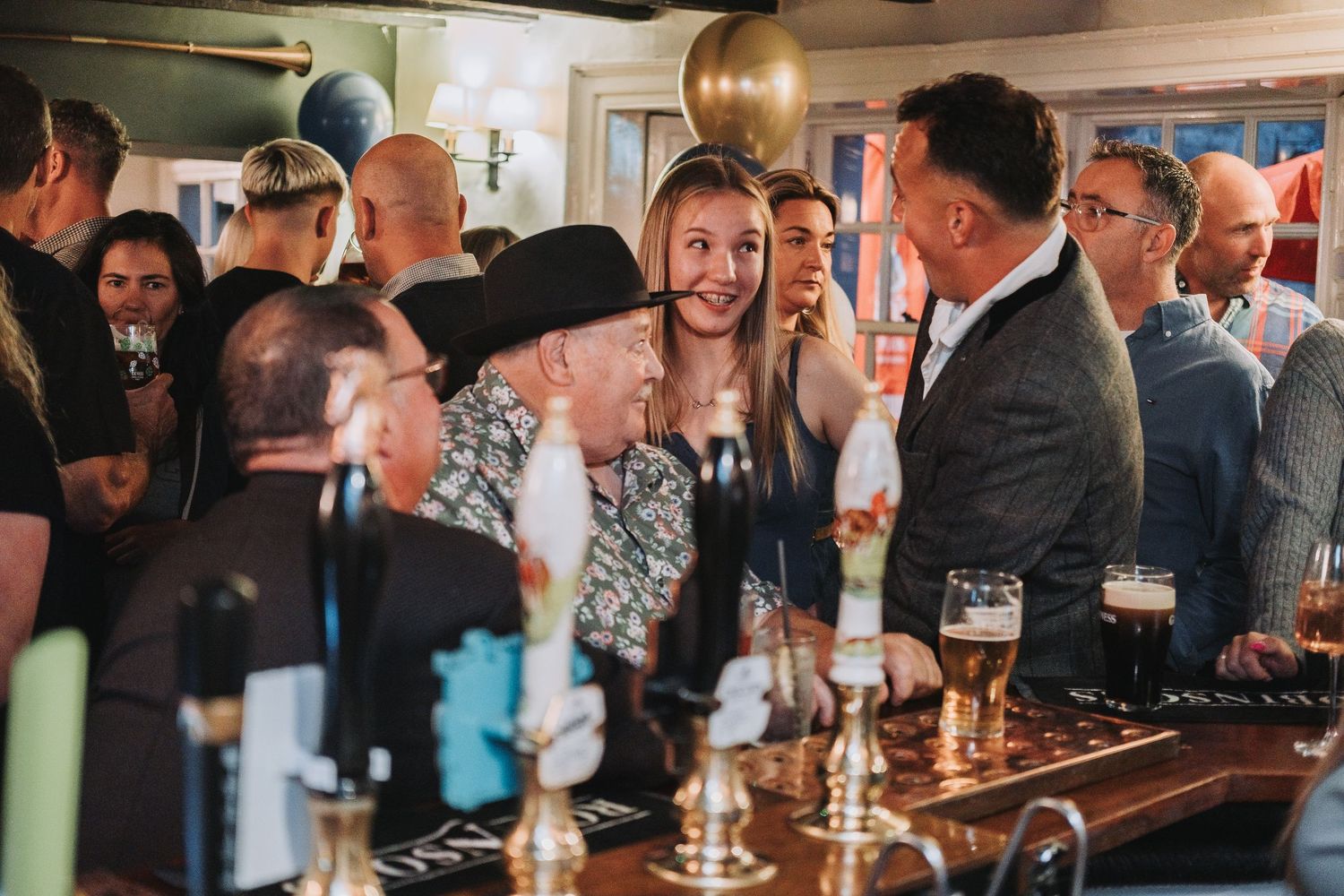 Groups of people enjoying drinks and conversation at an indoor social gathering.