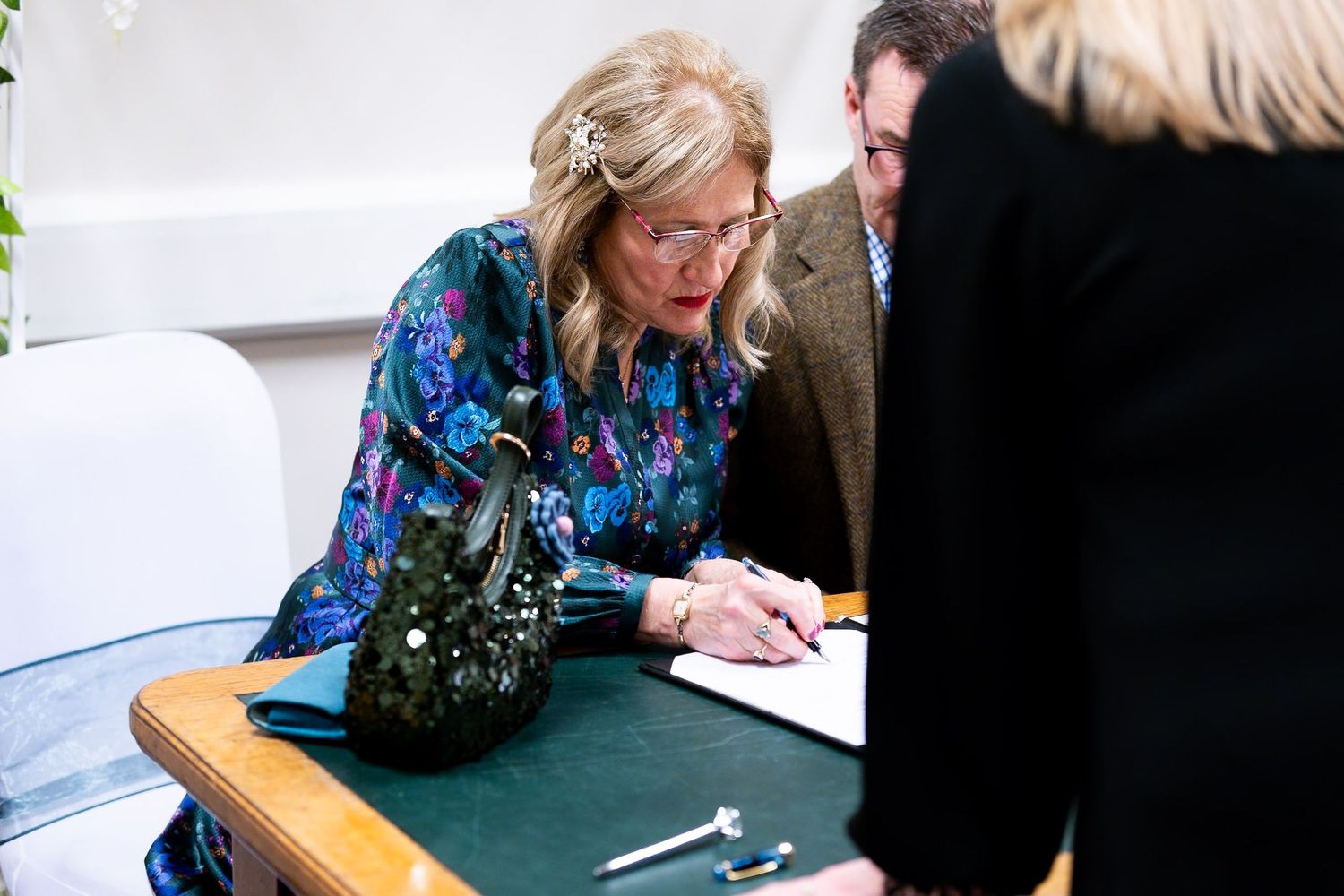 People signing documents at a table with a green tablecloth.