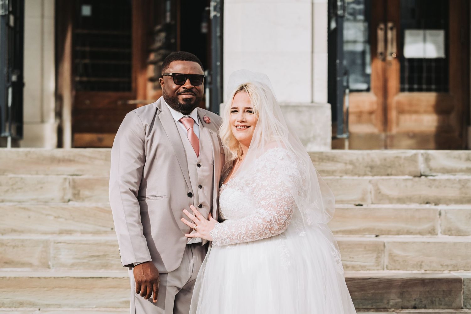 Wedding couple poses together on stone steps outdoors during their special day.