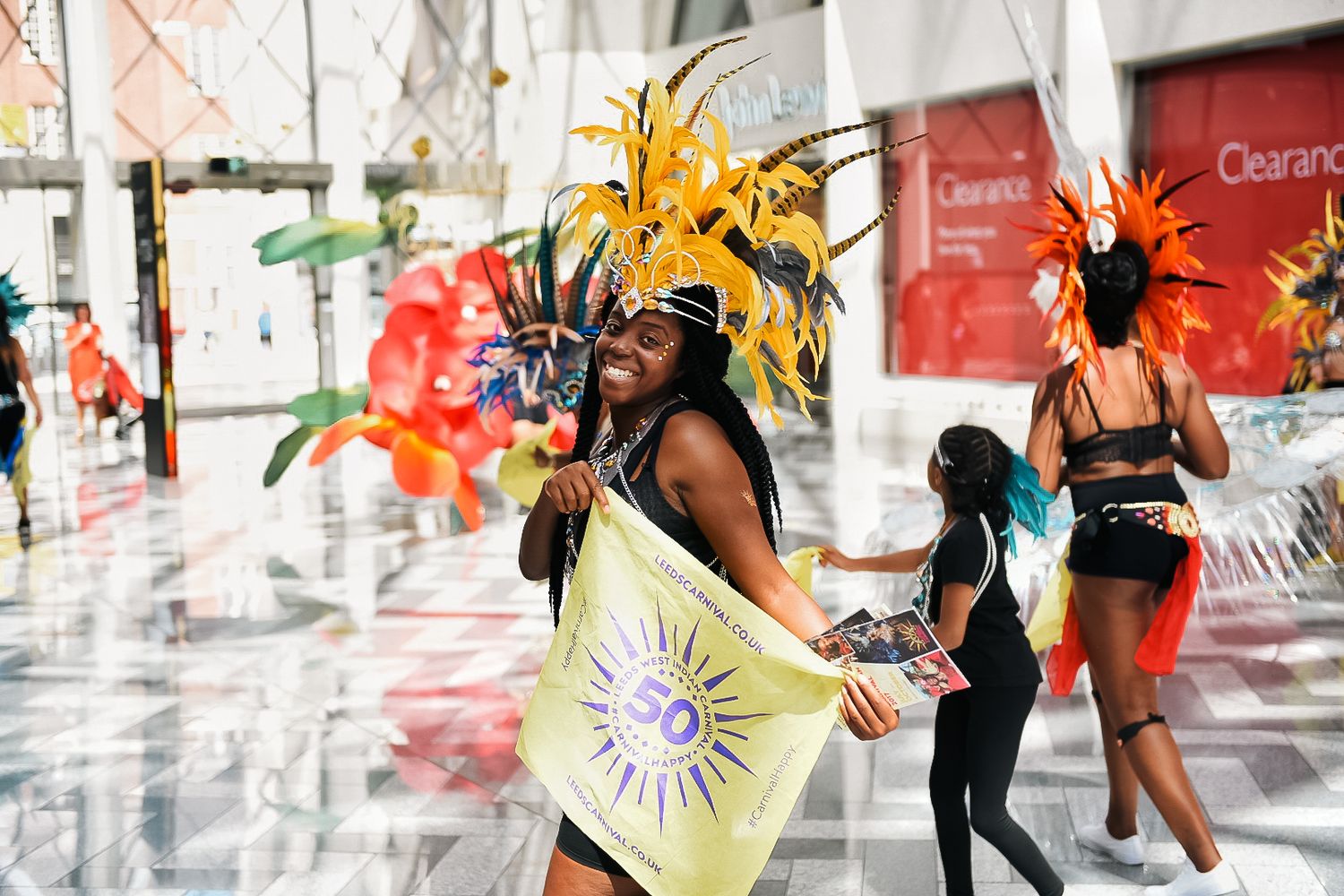 Carnival dancers in colorful feathered costumes performing in indoor venue shot in Leeds by 21 Photography