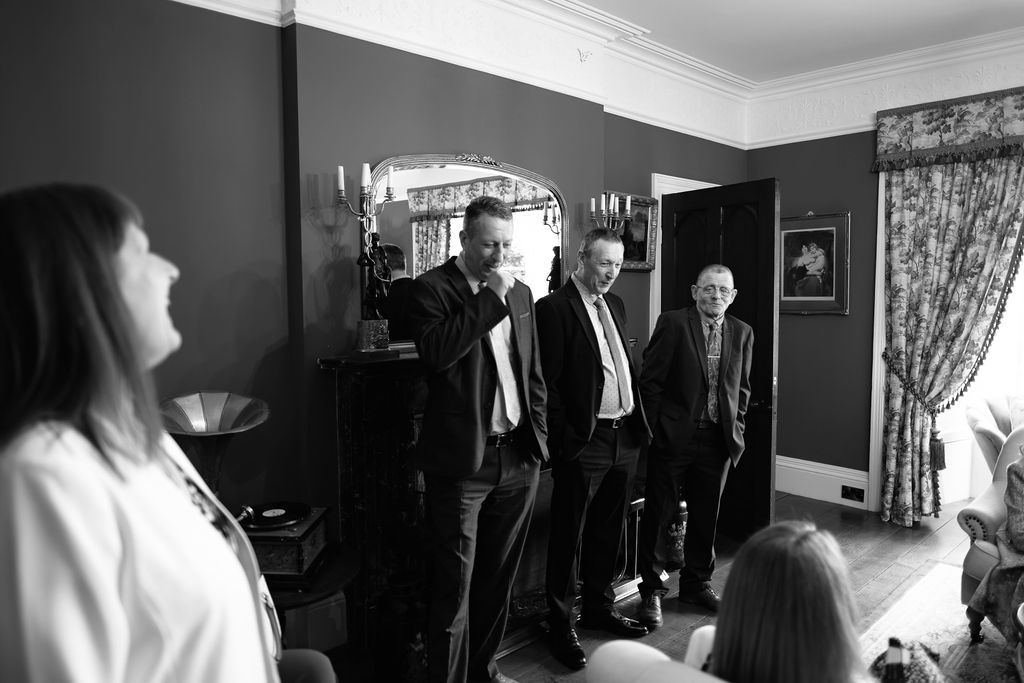 Group of men in suits talking beside a fireplace, black and white