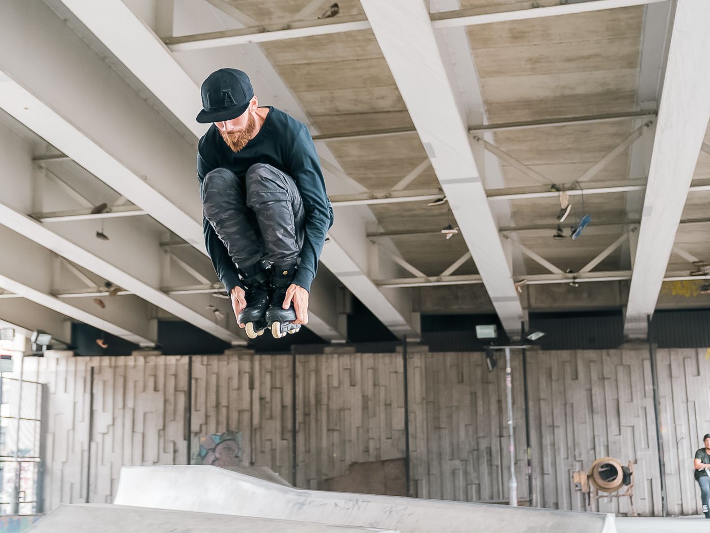 BMX rider crouches mid-air during trick jump in concrete indoor skate park shot in Leeds by 21 Photography