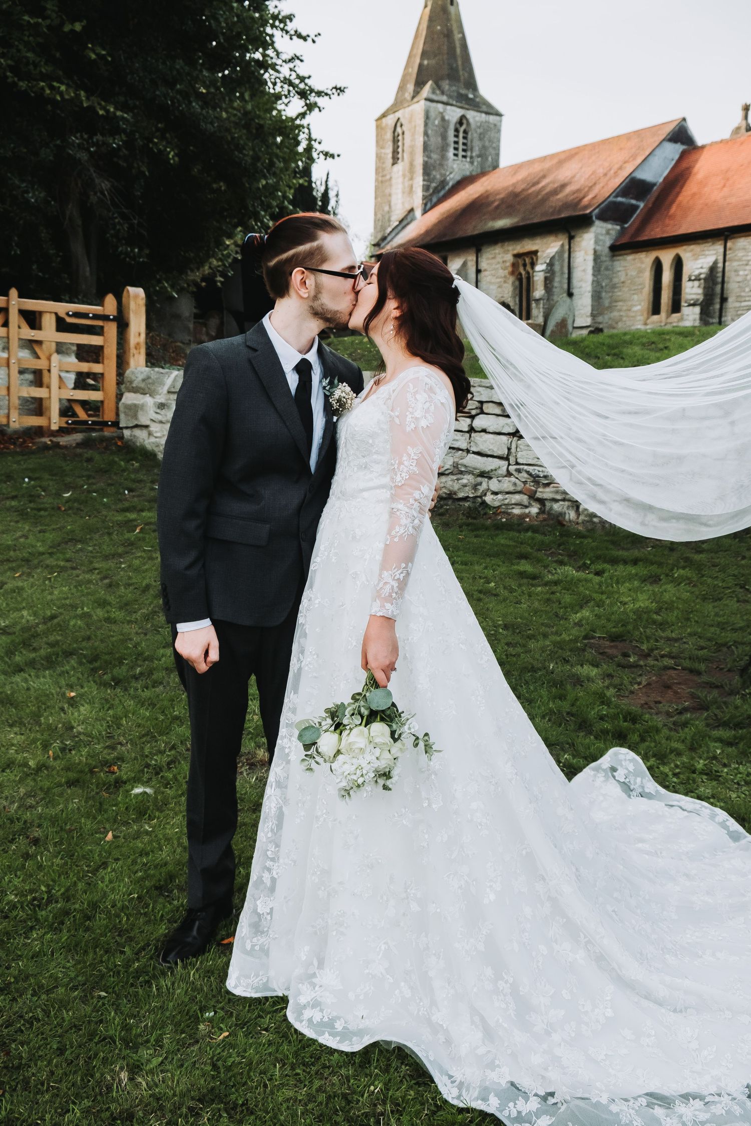 Romantic wedding photos with a flowing lace dress and church steeple in the background.