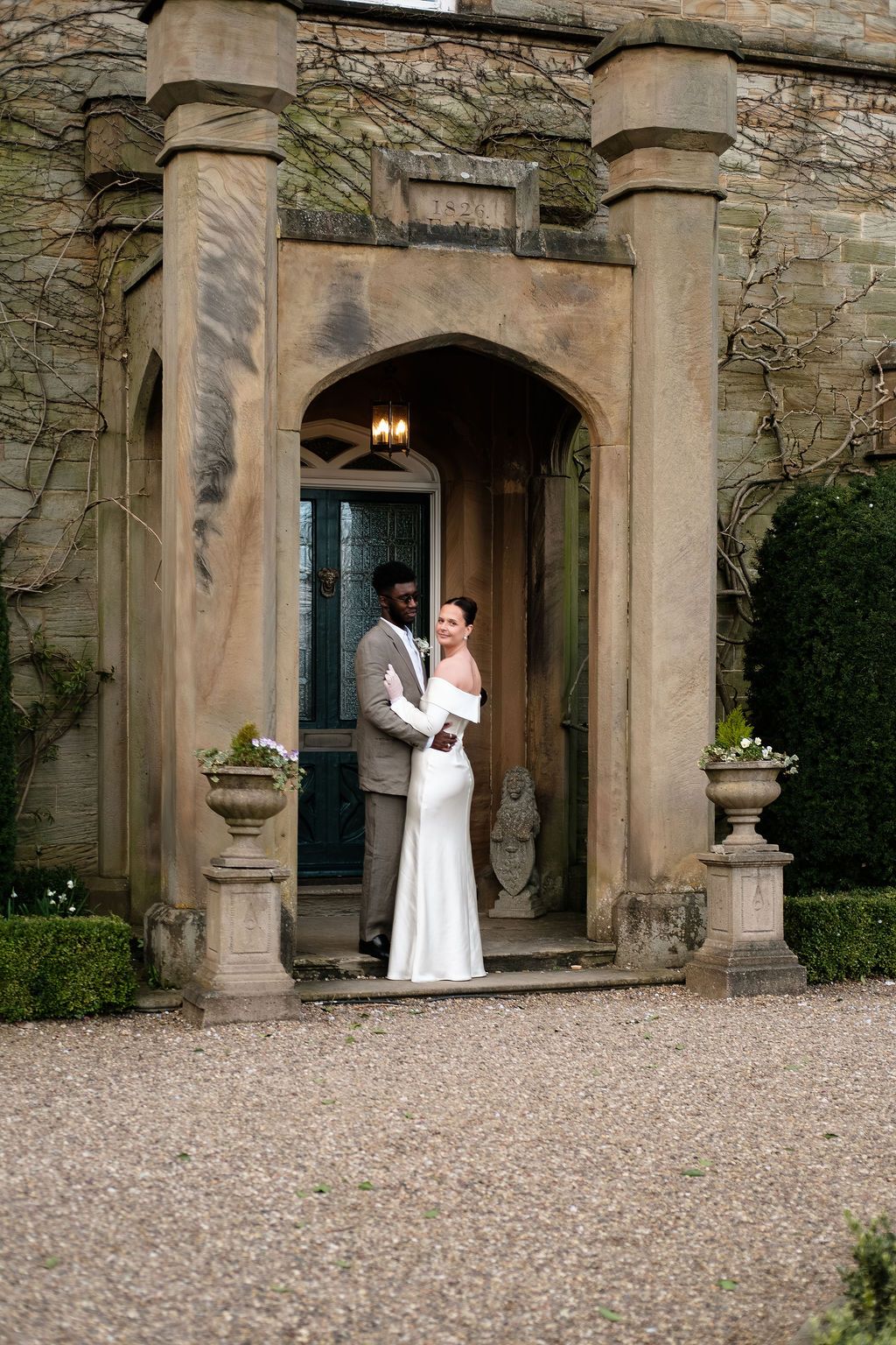 Couple embracing under a stone archway at Dunston Hall's front door