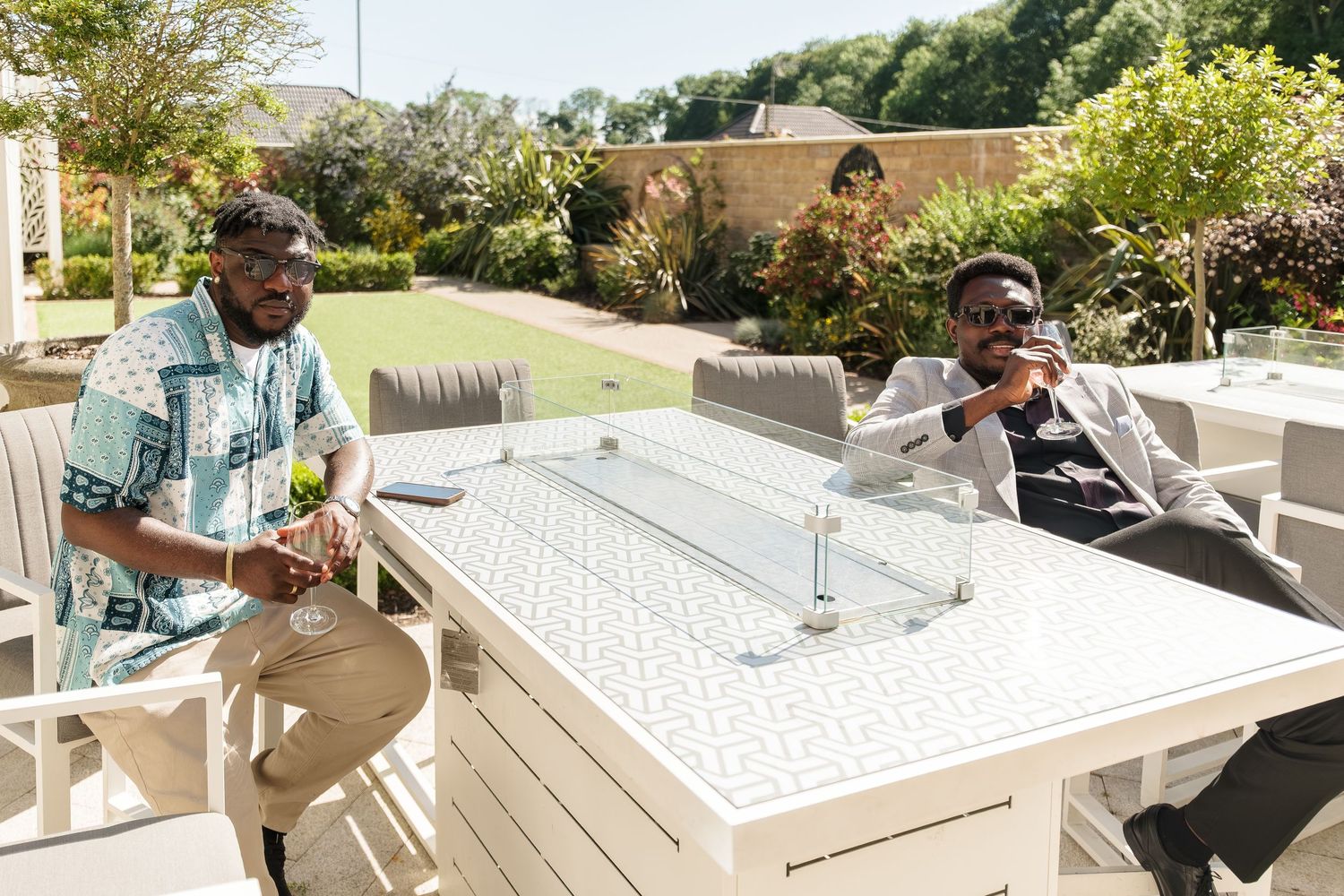 Two men relaxing outdoors at a patio table on a sunny day in a green garden setting at Wildes Inn, Chesterfield taken by 21 Photography