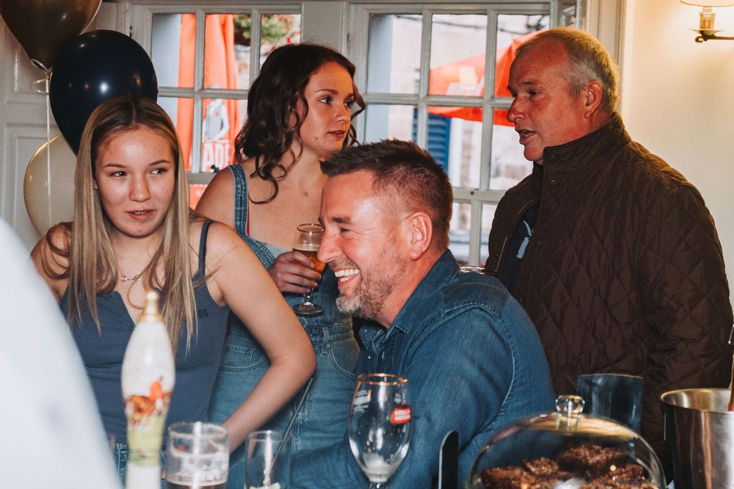 A casual gathering of people socializing and laughing together around drinks at a bar or restaurant.