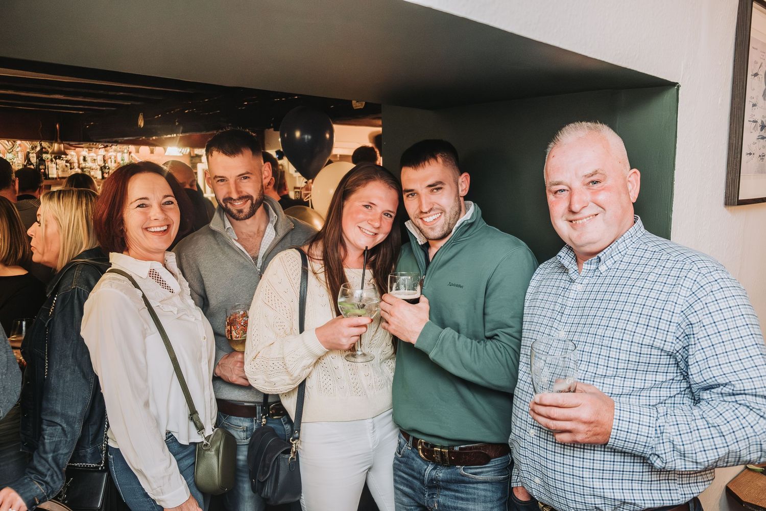 Partygoers in casual attire socializing and enjoying drinks at an indoor gathering space.
