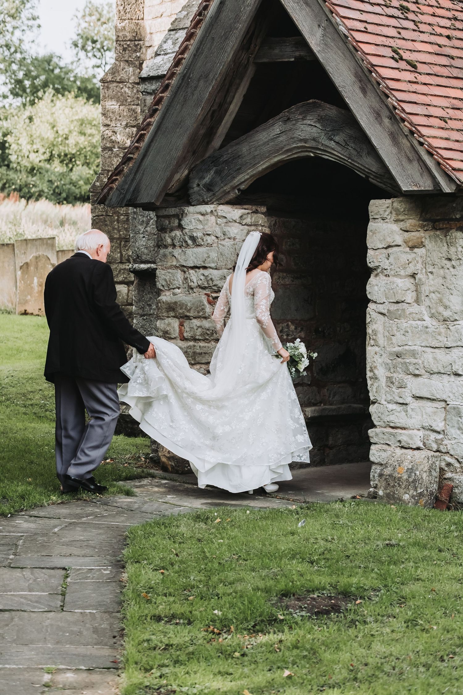 A wedding couple enters a rustic stone church entrance in a sequence of candid moments captured on grass.