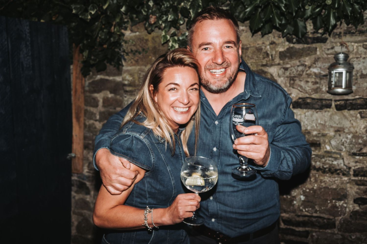 Couples enjoying drinks and celebrating against a rustic stone wall backdrop.