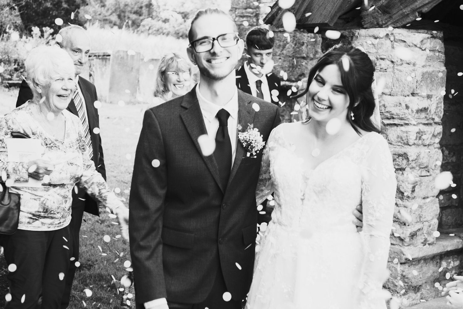A black and white wedding photo collage showing candid moments of a bride and groom at their celebration.