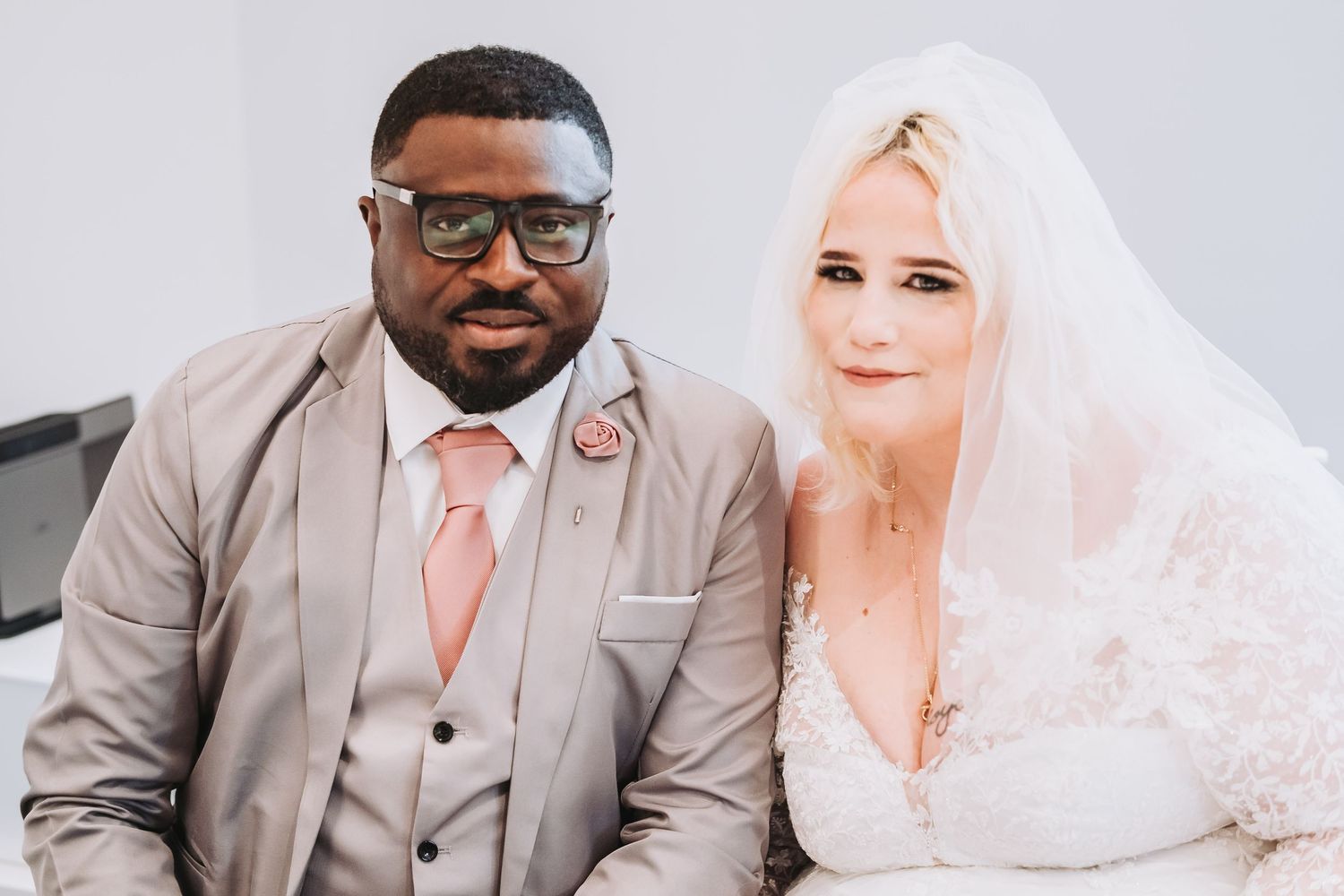 A couple celebrates their wedding day, wearing formal attire with the bride in white and groom in grey.