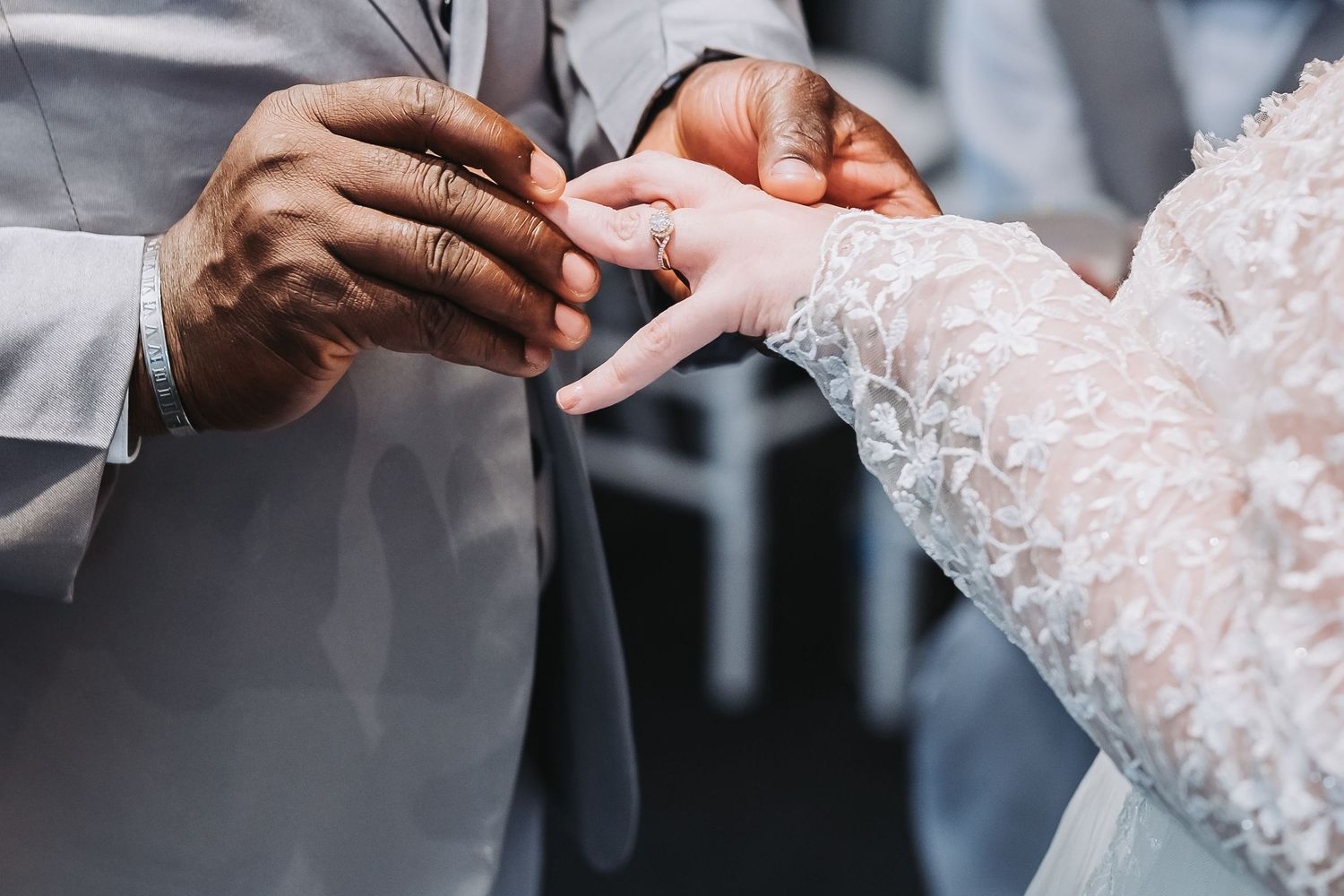 Close-up view of hands exchanging wedding rings during an elegant ceremony.
