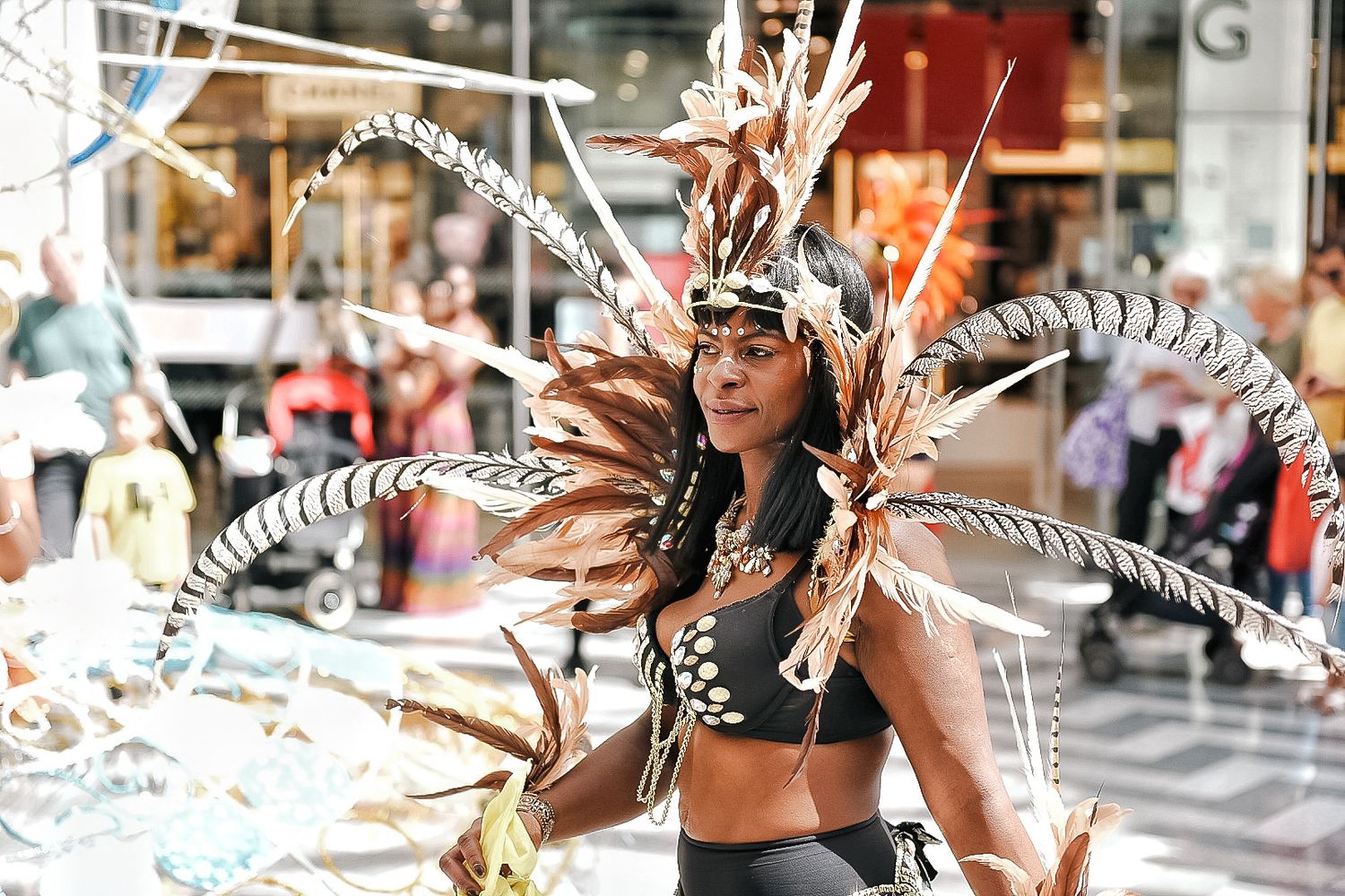 Colorful street scene with people wearing feathered headdresses and decorative accessories shot in Leeds by 21 Photography