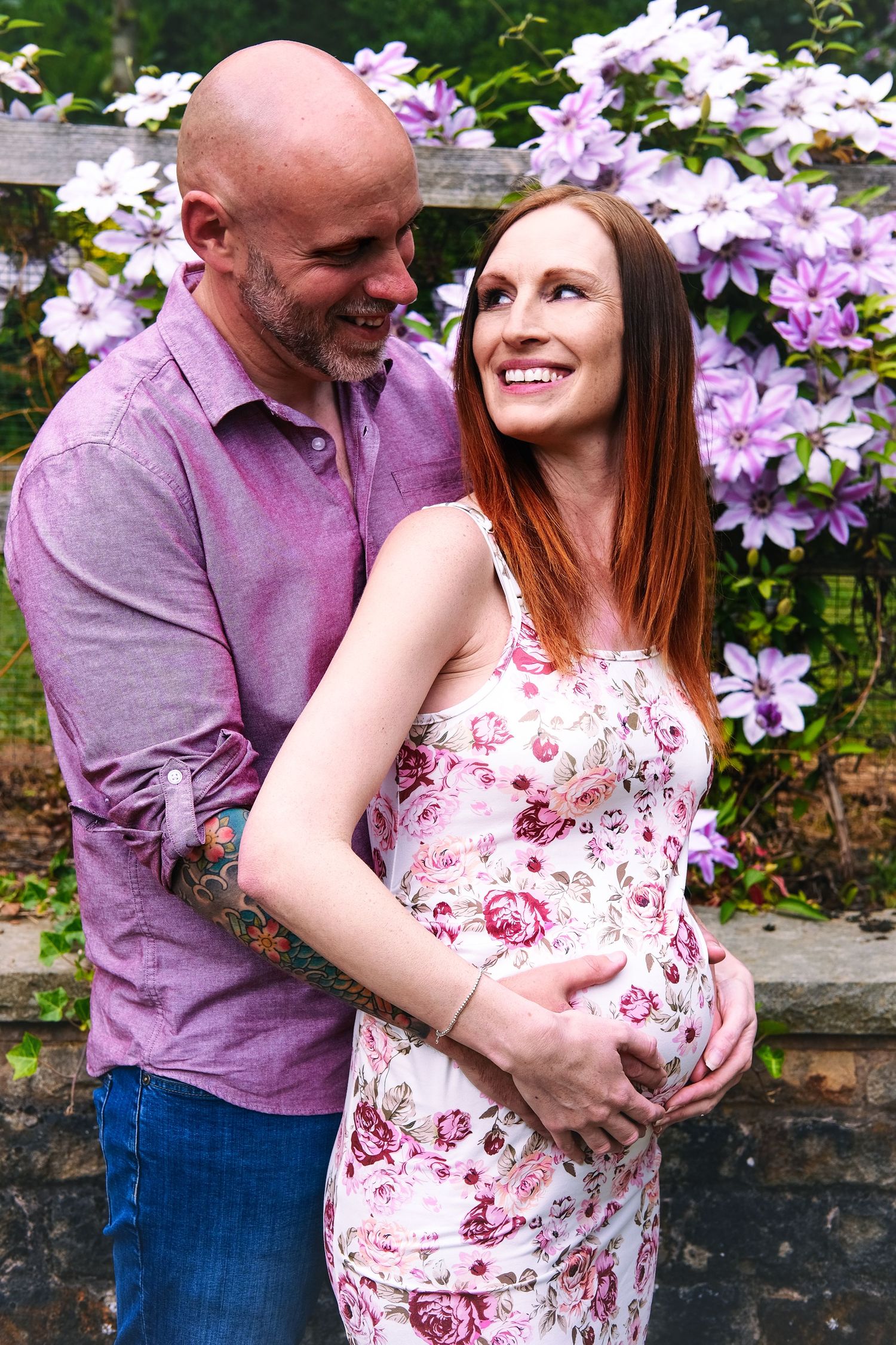 Romantic maternity photos with purple clematis flowers in the background.
