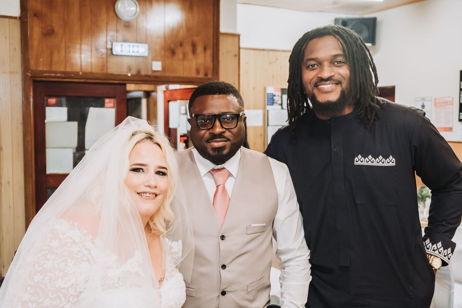 Wedding party celebrating with bright smiles in a wood-paneled reception venue.