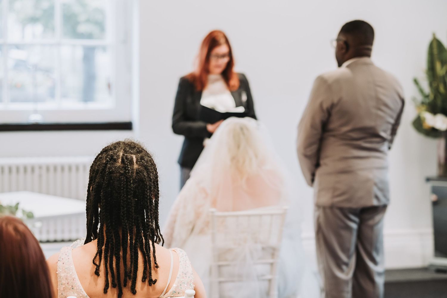 People gathering in a bright indoor space with white walls and large windows during a professional meeting or ceremony.
