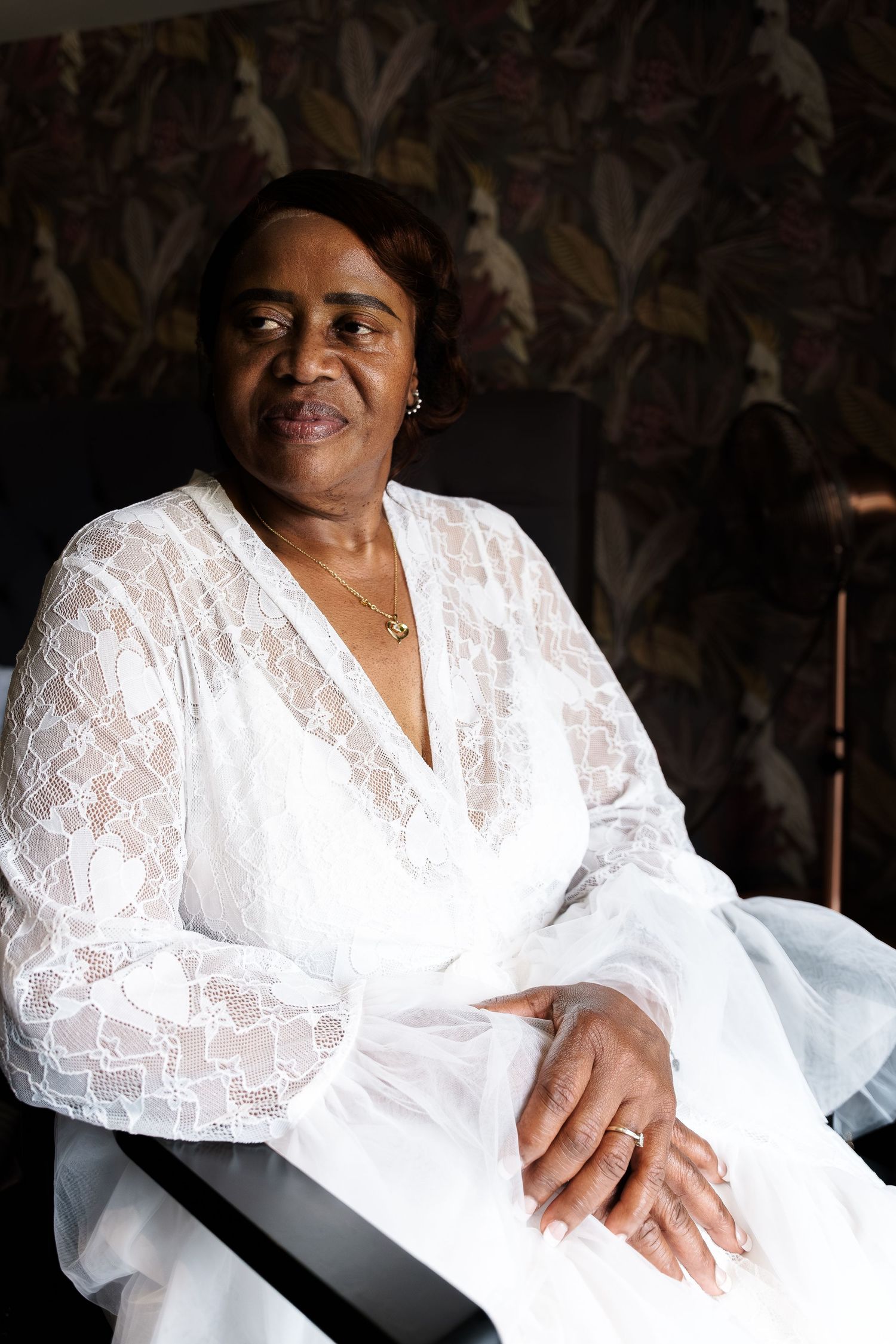 Elegant woman in white lace robe sitting in a chair against floral wallpaper background. at Wildes Inn, Chesterfield taken by 21 Photography