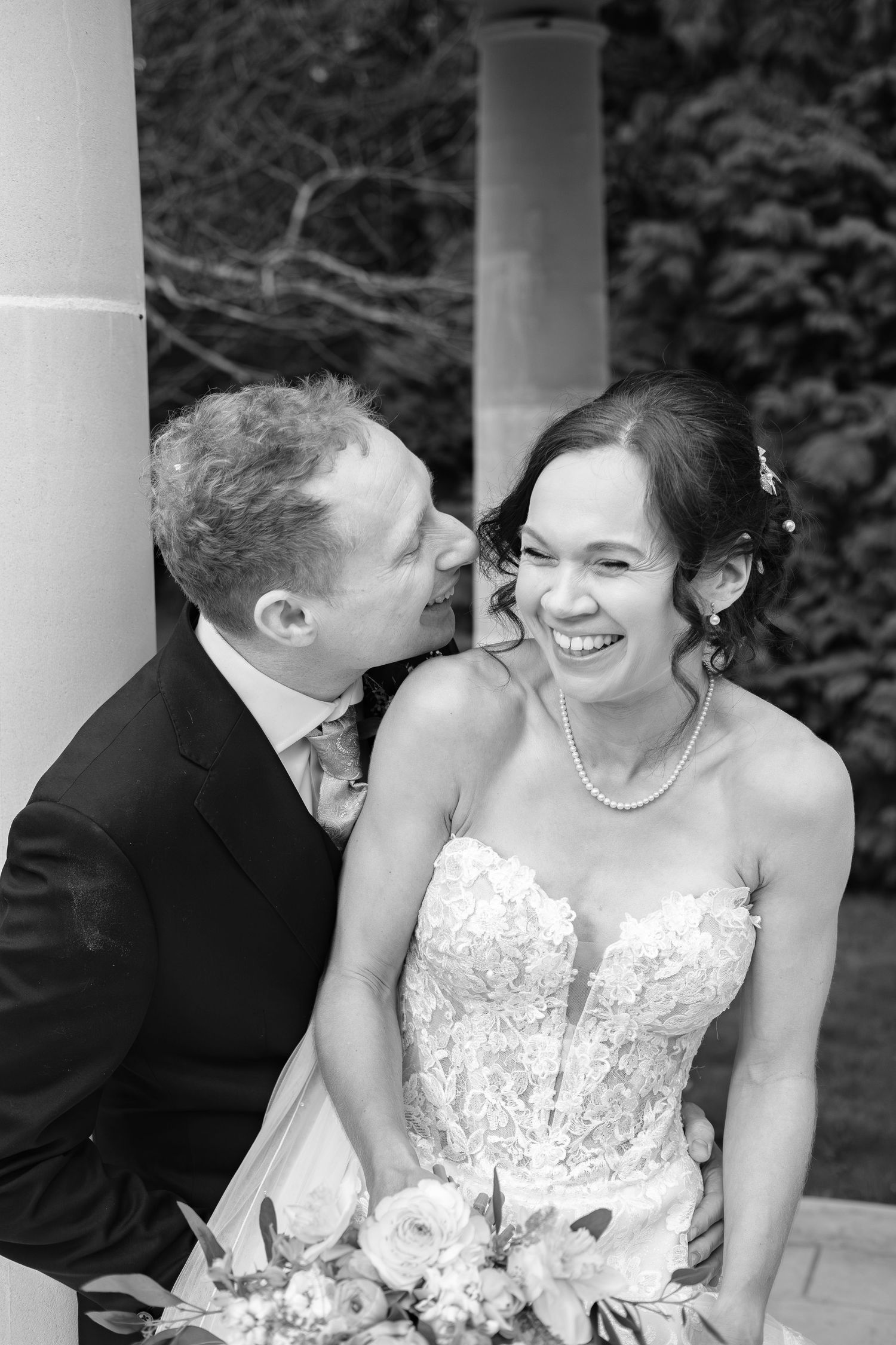 Black and white wedding photo of smiling bride in lace gown and groom in suit sharing a tender moment outdoors  at dunston hall estate