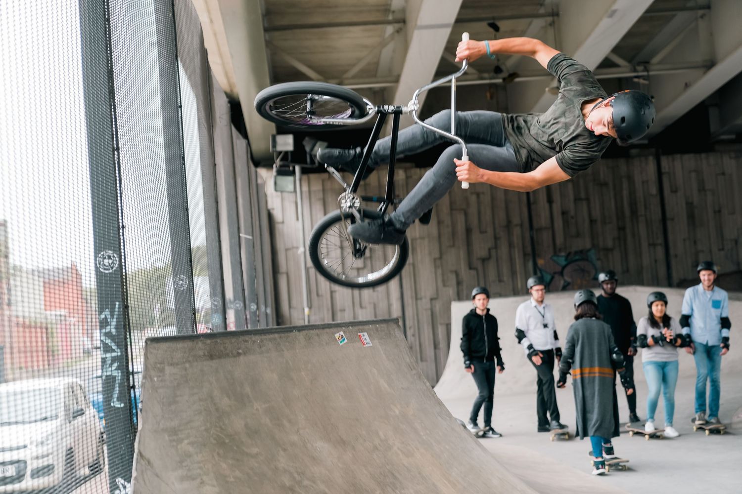 BMX rider performs impressive aerial stunt on indoor ramp with spectators watching in background shot in Leeds by 21 Photography