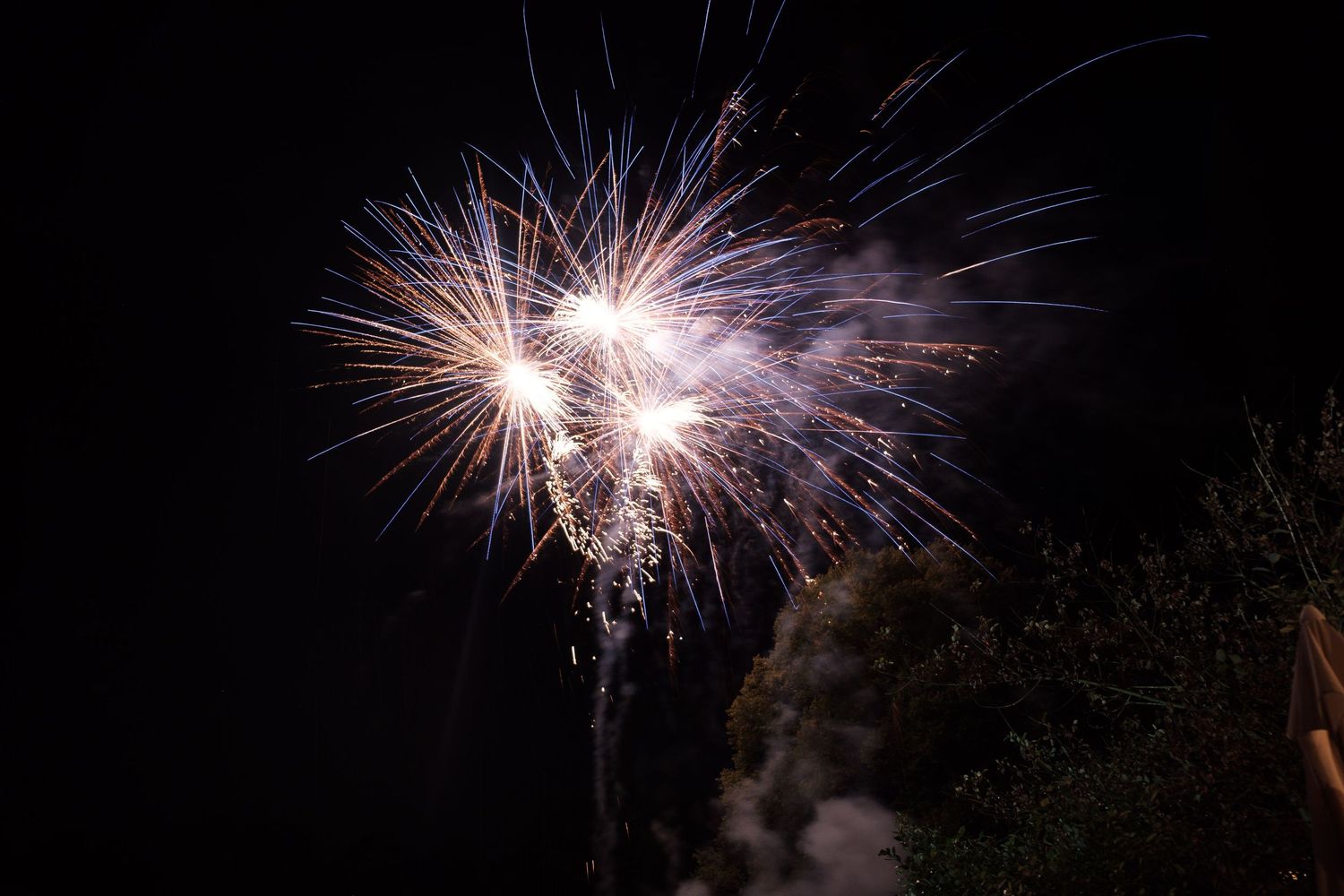 Pink and white fireworks explode against a dark night sky creating a spectacular light display.