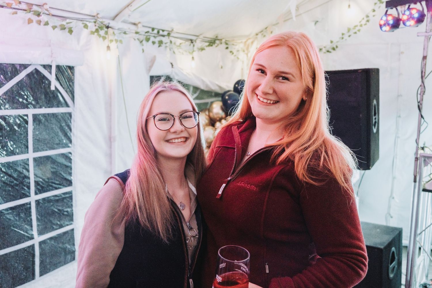 Partygoers celebrating in a decorated indoor space with greenery and fairy lights.