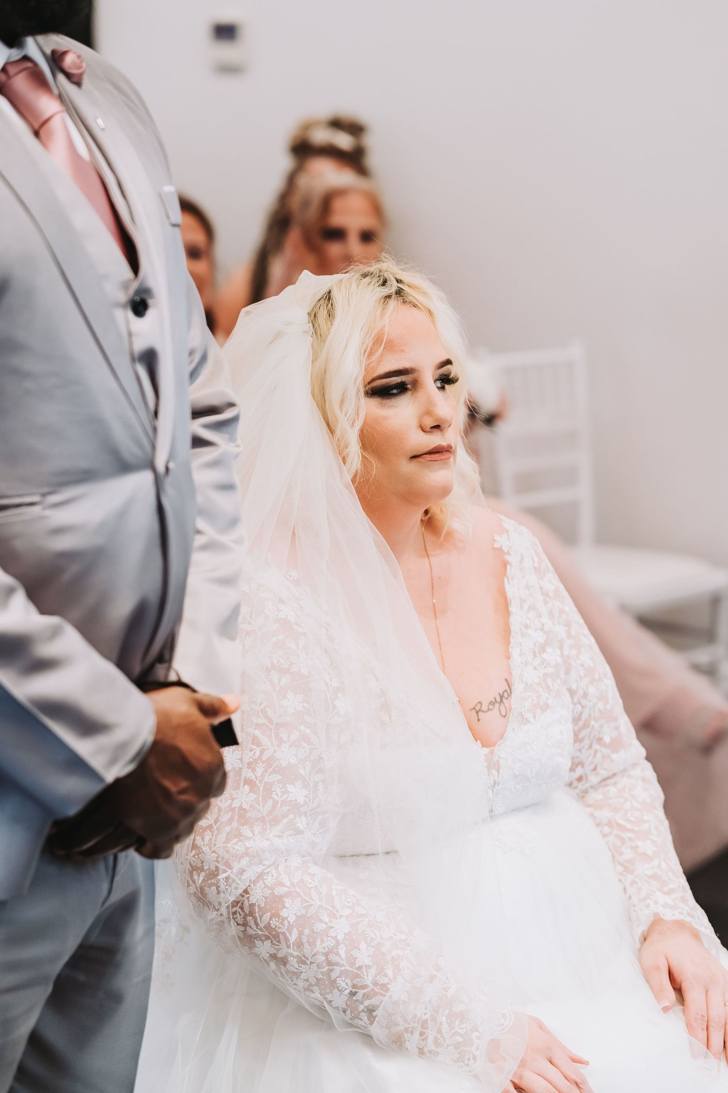 Bride in an elegant white lace wedding dress prepares for her ceremony with delicate details on her gown.