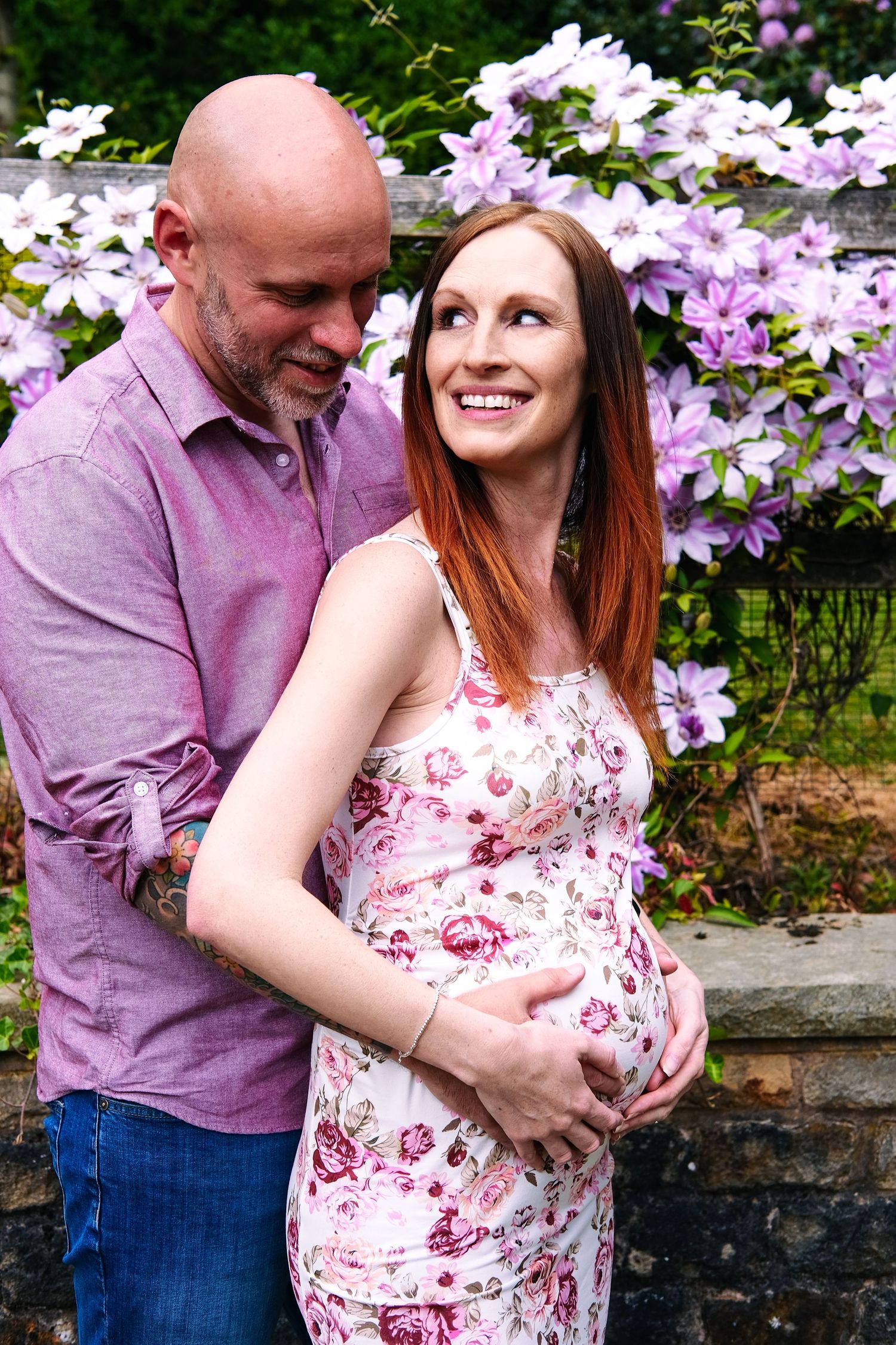 Joyful couple shares loving moments among blooming purple flowers.