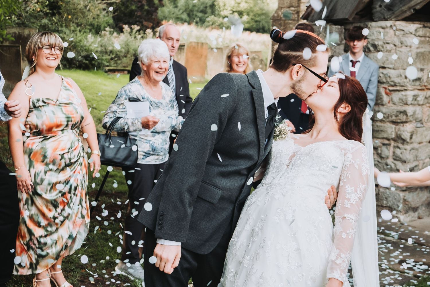 Guests throw confetti celebrating Tyson and Rebecca’s vow renewal outdoors in Derbyshire.