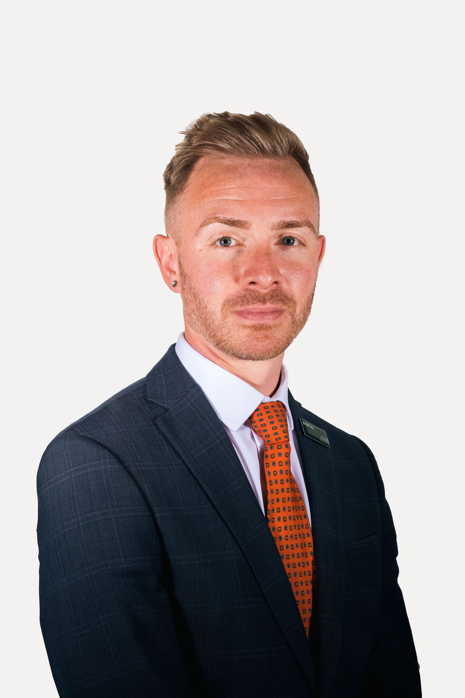 Professional headshot of businessman in navy suit with orange tie against white background shot in Leeds by 21 Photography